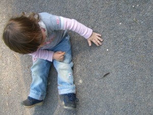 Kind sitzt am Boden mit einer Schnecke
